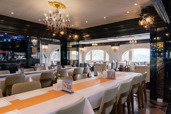 Un ristorante con diversi tavoli, lampadari e un'area bar.