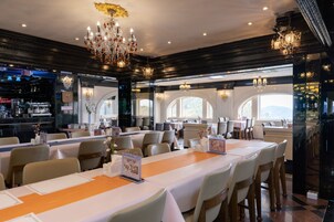 Ein Restaurant mit mehreren Tischen, Kronleuchtern und einer Bar.