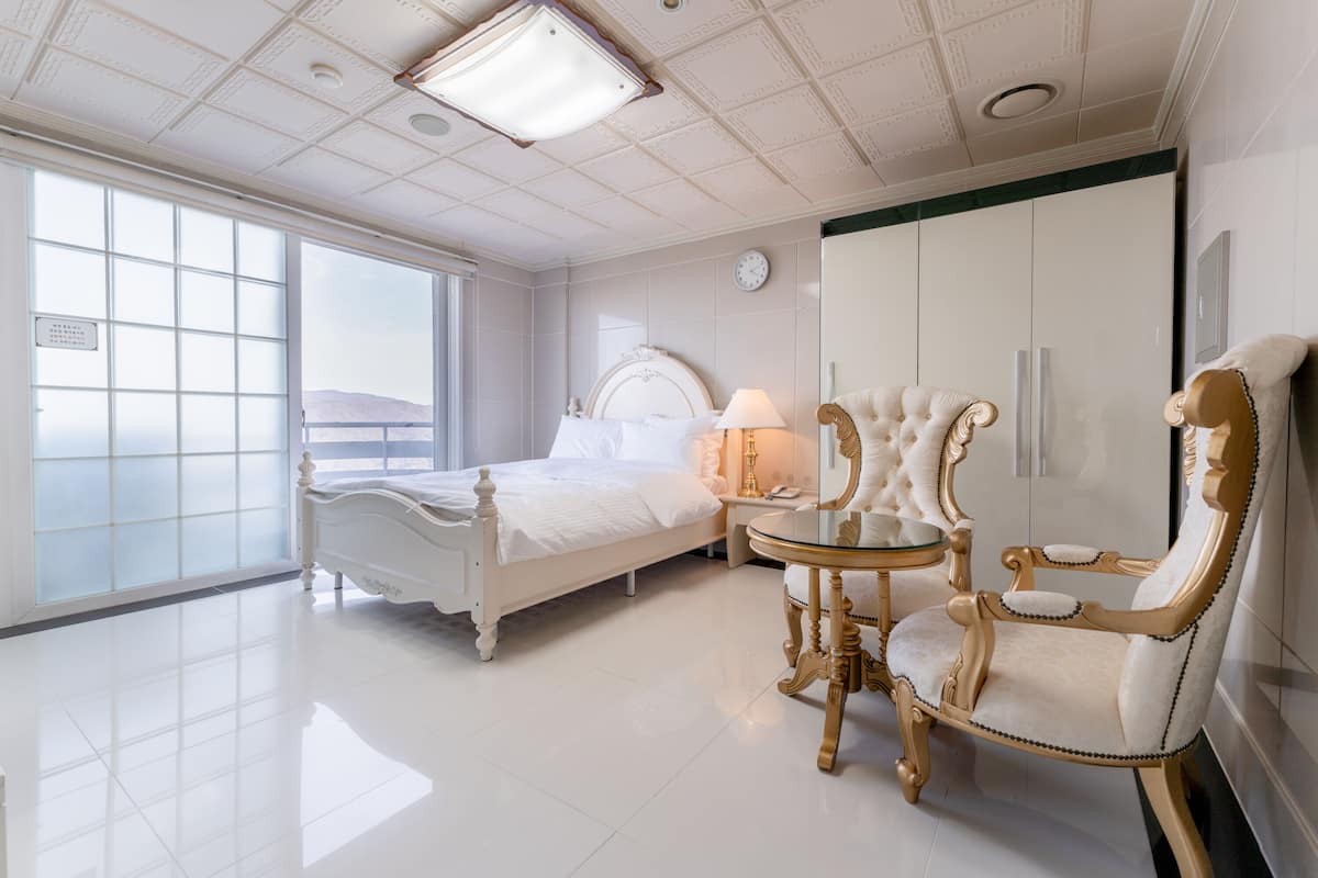 Une chambre spacieuse avec un grand lit, une coiffeuse avec un miroir, une chaise et une armoire.