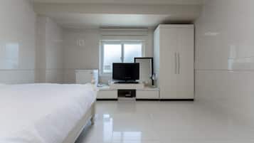 Een moderne hotelkamer met een bed, een televisie, een kledingkast en een raam met luxaflex.