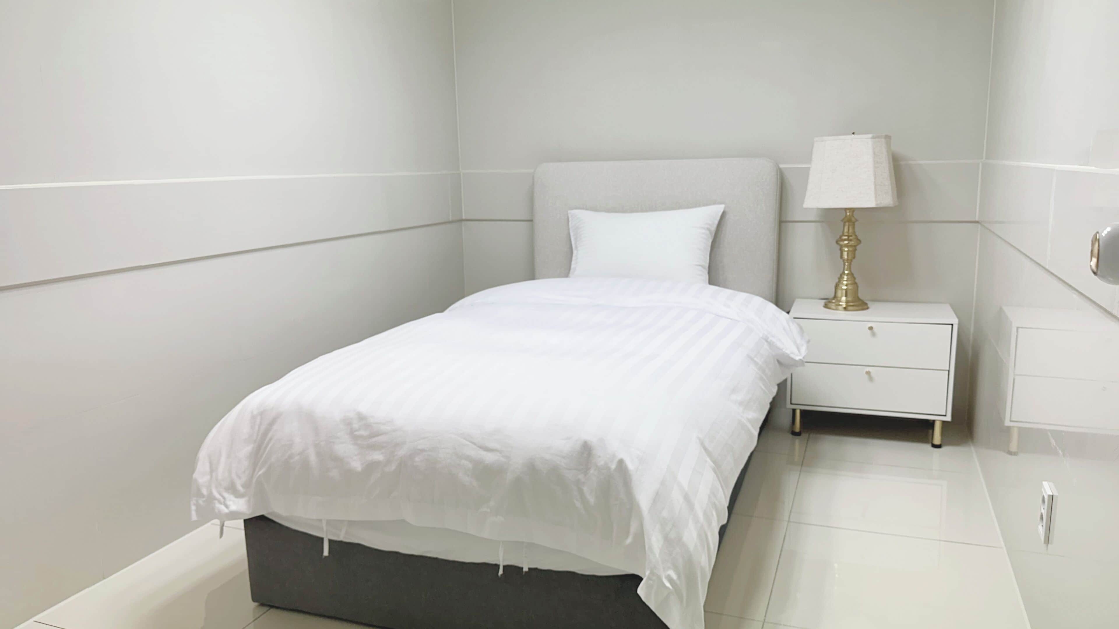 A modern bedroom with a bed, a bedside table, and a lamp.