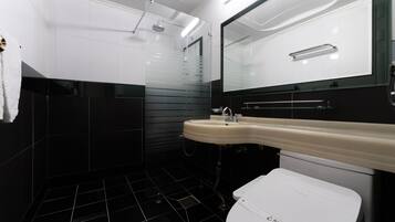 A modern bathroom with a white sink, black tiles, and a glass shower enclosure.
