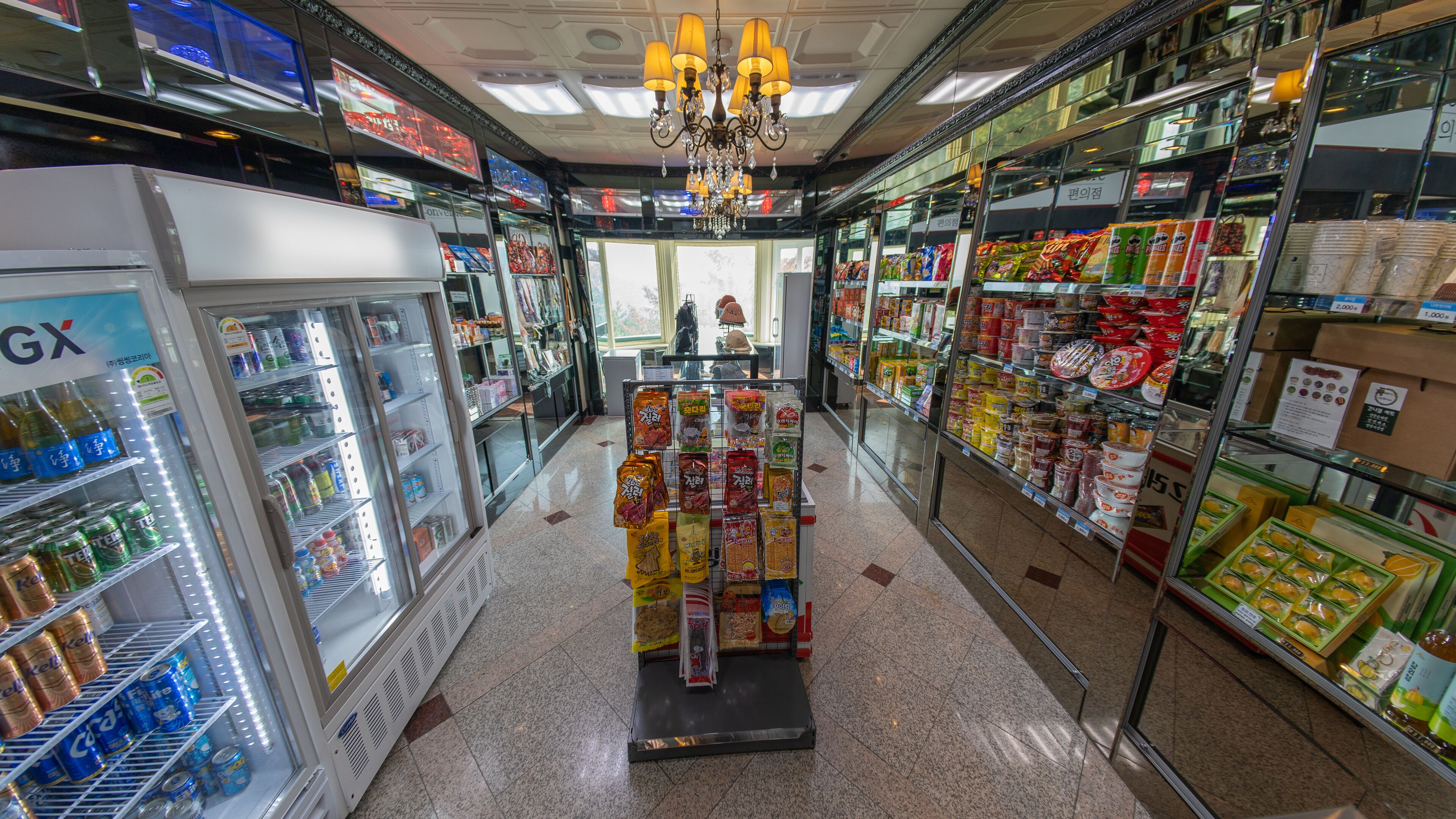 A grocery store aisle with refrigerated sections on the left and shelves stocked with various products on the right.