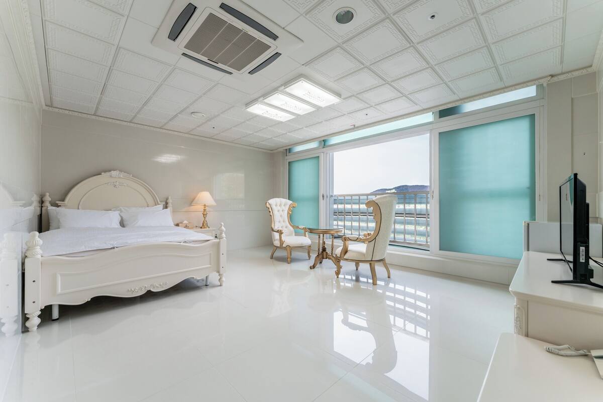Une chambre d’hôtel avec un grand lit, un bureau, une chaise et une fenêtre donnant sur un beau paysage.