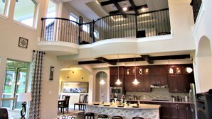 A spacious kitchen with a high ceiling, a mezzanine level, and a dining area with a view of the kitchen.