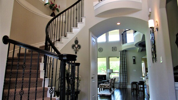 A spacious interior with a grand staircase, a living area with seating, and a view of the outdoors.