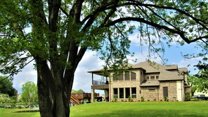 A two-story house with a brick exterior, large windows, and a covered porch.