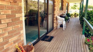 Terraza de madera con felpudo, cesta de mimbre y mobiliario exterior.