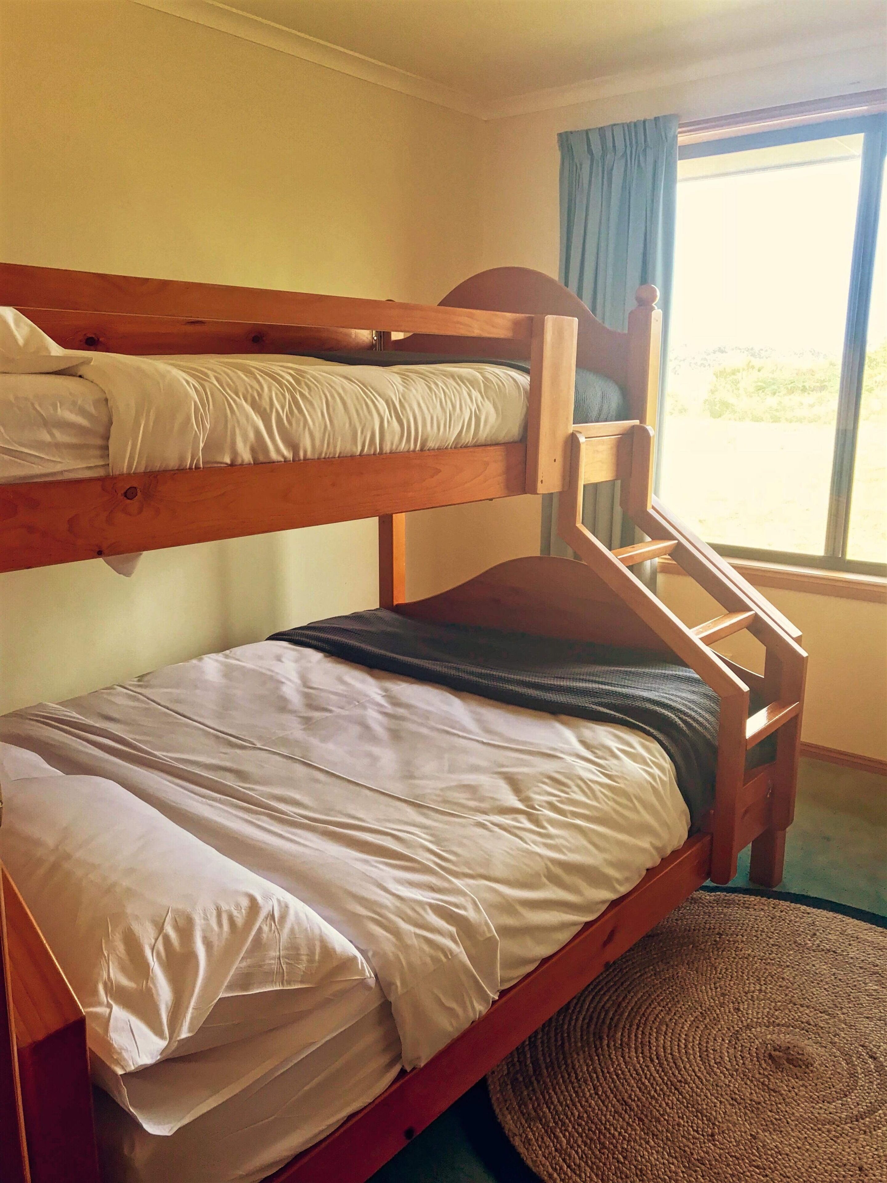 A bunk bed room with a window and curtains.