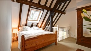 Ein Schlafzimmer mit einem hölzernen Bett, einem Fenster, einer weißen Geländer und einer Pflanze.