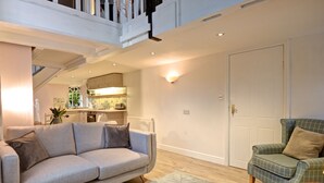 Ein Wohnzimmer mit grauem Sofa, grünem Sessel und einem gemusterten Teppich.