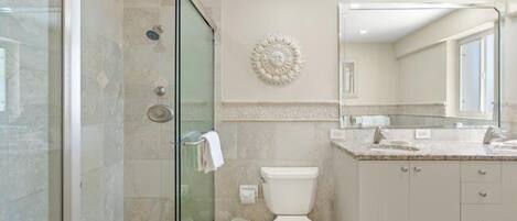 Une salle de bain moderne avec une douche à parois de verre, des toilettes, un lavabo et un grand miroir.