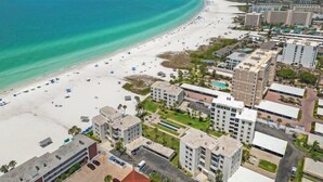 An aerial view of a coastal area with a beach, buildings, and a clear sky. - Island House Beach Resort 14S (Siesta Key)