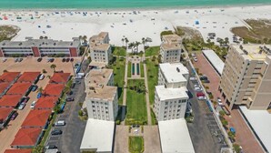 An aerial view of a coastal hotel with multiple buildings, a parking lot, and a beach in the background. - Island House Beach Resort 14S (Siesta Key)