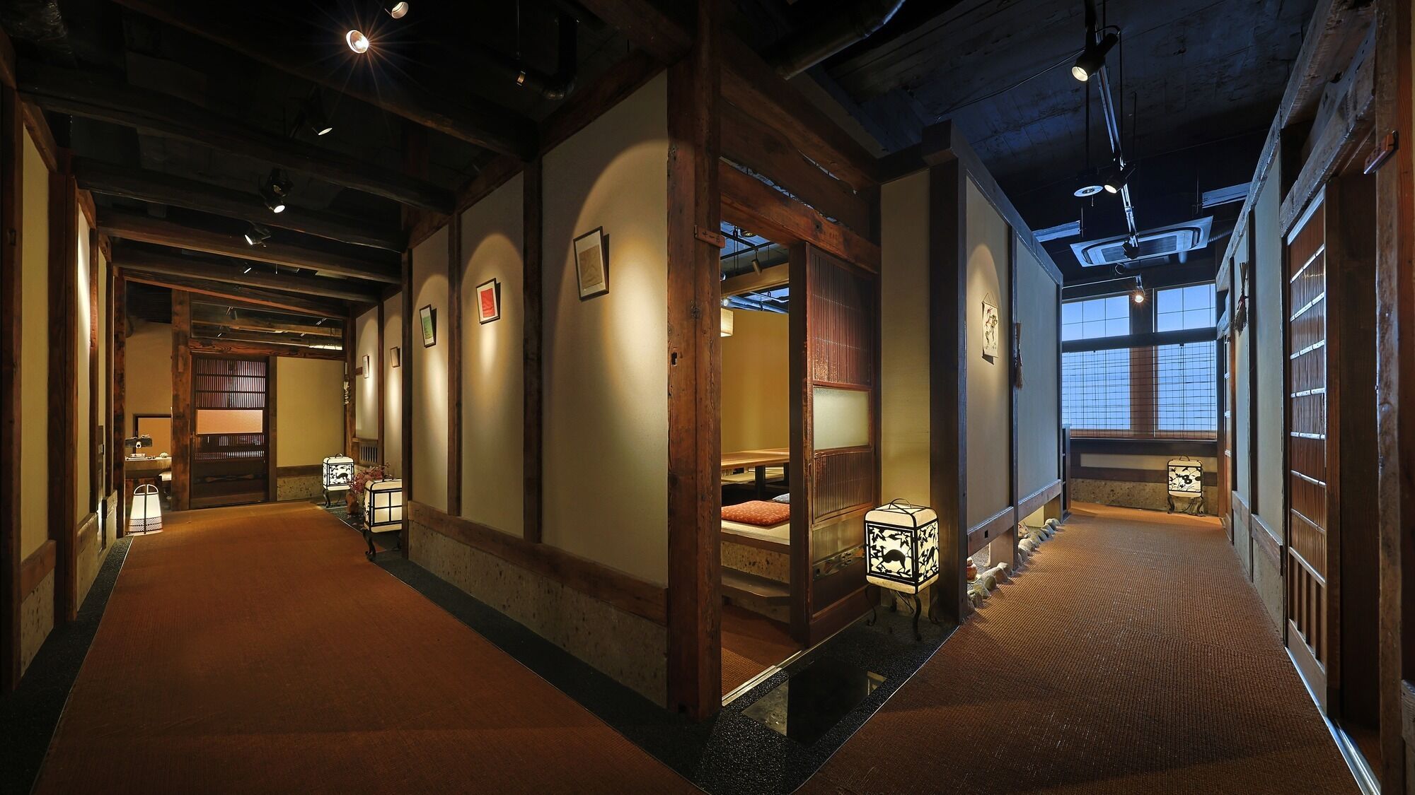 A traditional Japanese inn with tatami mat flooring, wooden beams, and sliding doors.
