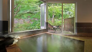 A spa area with a glass door leading to a garden, a stone bench, and a lounge chair.