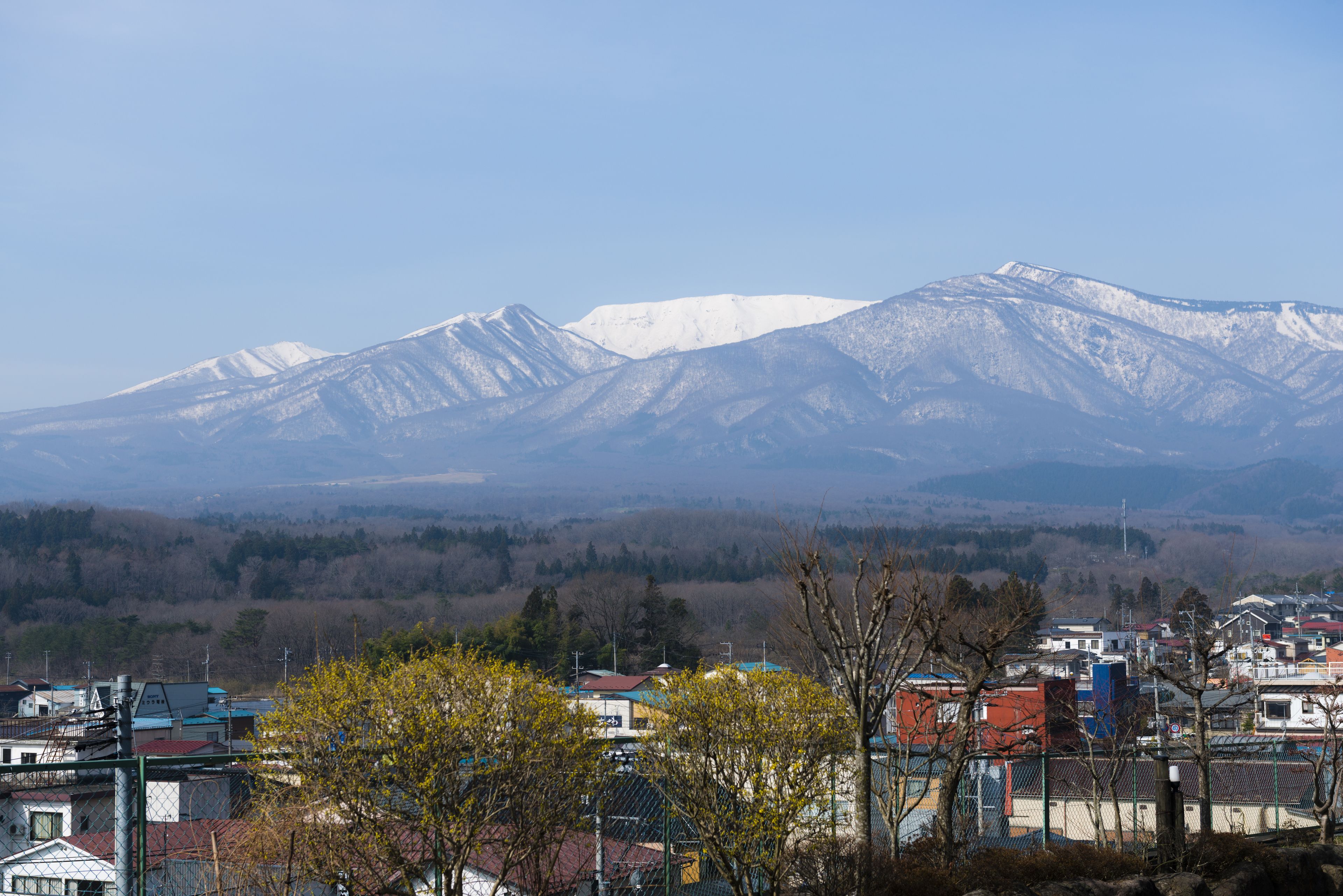 Uma cidade com edifícios em primeiro plano e montanhas nevadas ao fundo.