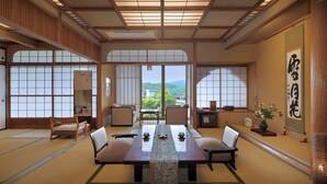 A traditional Japanese-style room with tatami flooring, a low table with cushions, and sliding doors with a view of greenery.