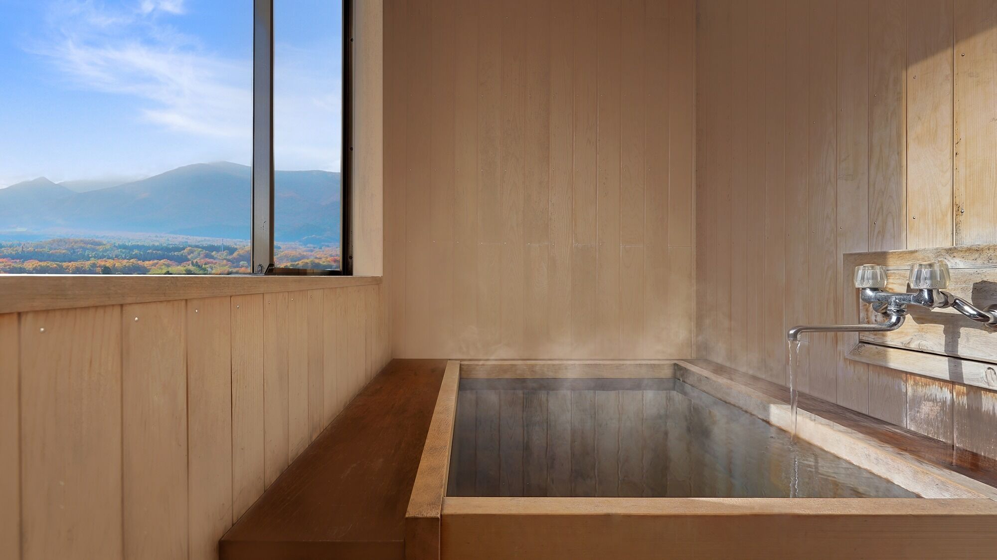 Una habitación de madera con un ventanal grande, una bañera y vistas a las montañas.