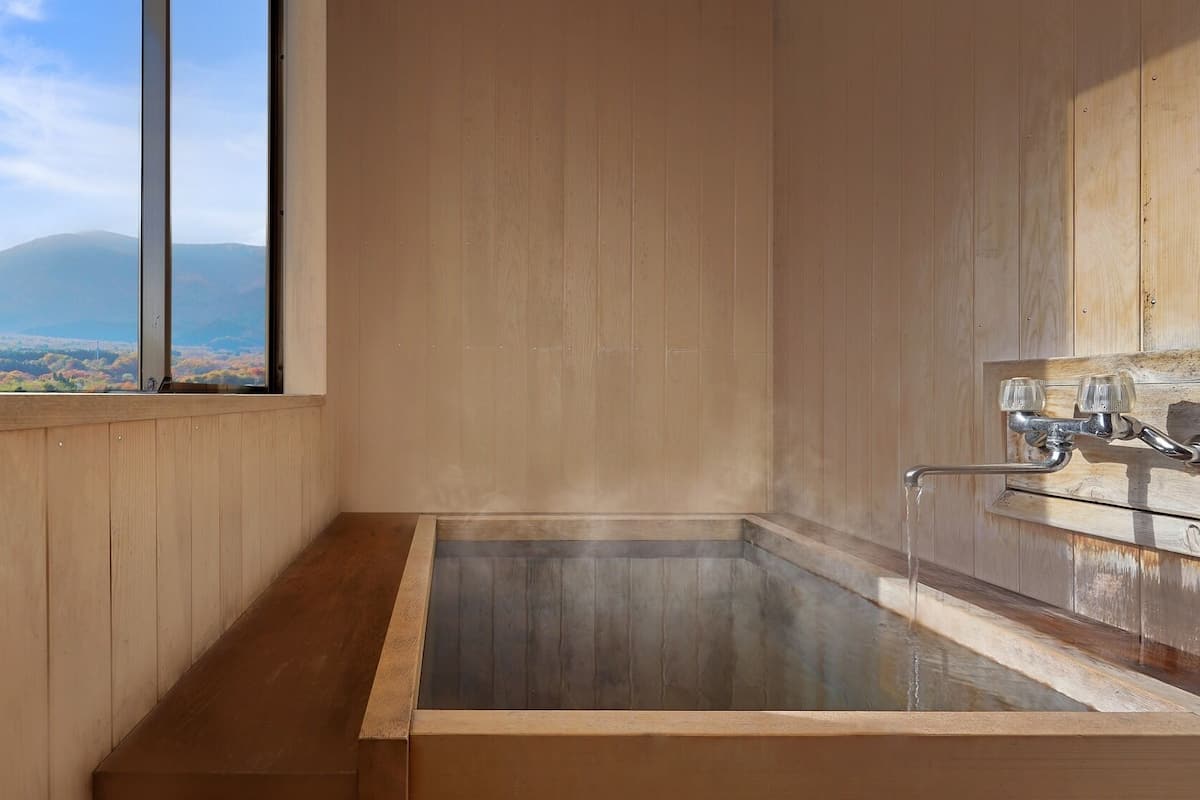 A wooden interior with a large window, a glass-enclosed hot tub, and a wooden floor.