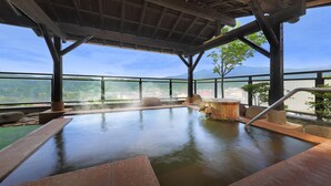 A hot spring bath area with a view of mountains and a clear sky.