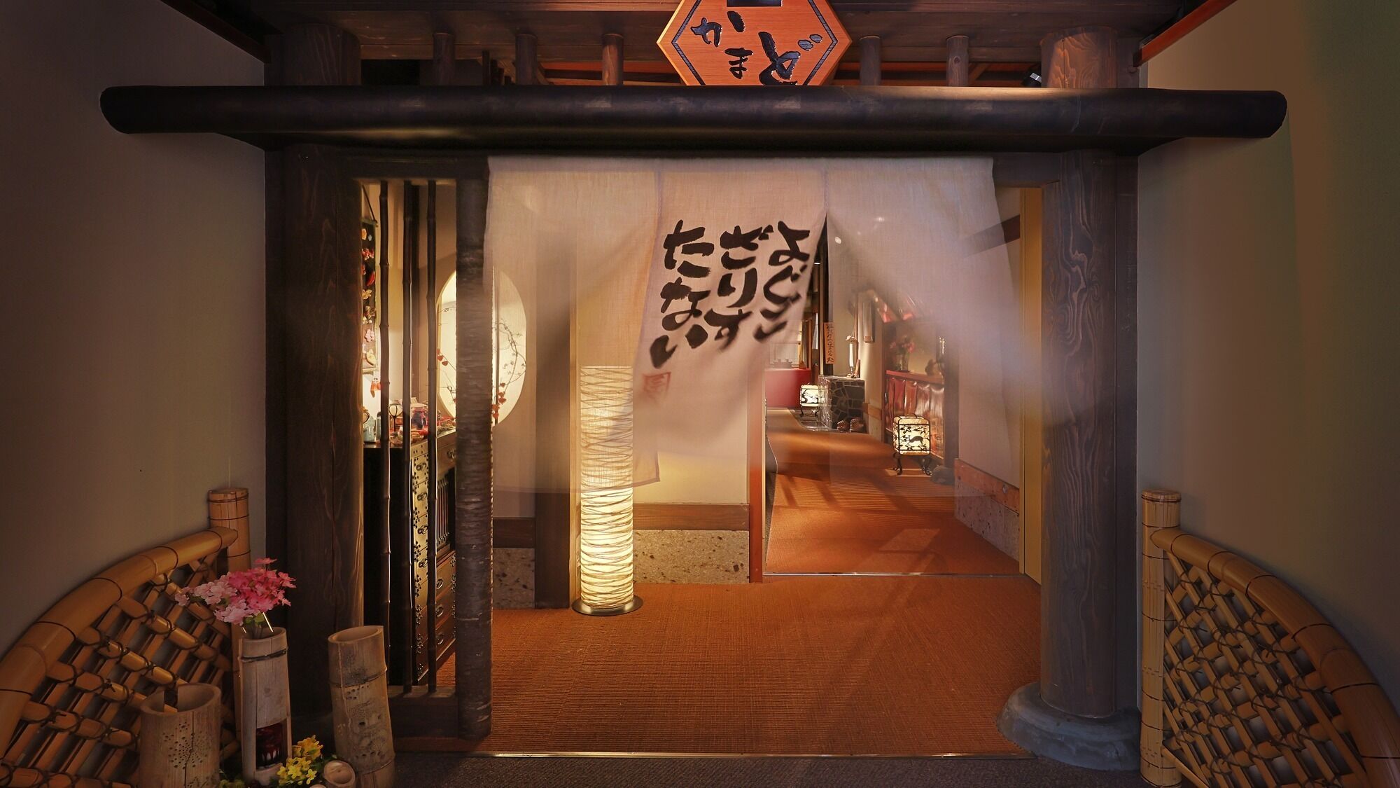 A traditional Japanese entrance with a wooden torii gate, a shimenawa rope, and a hanging shide.