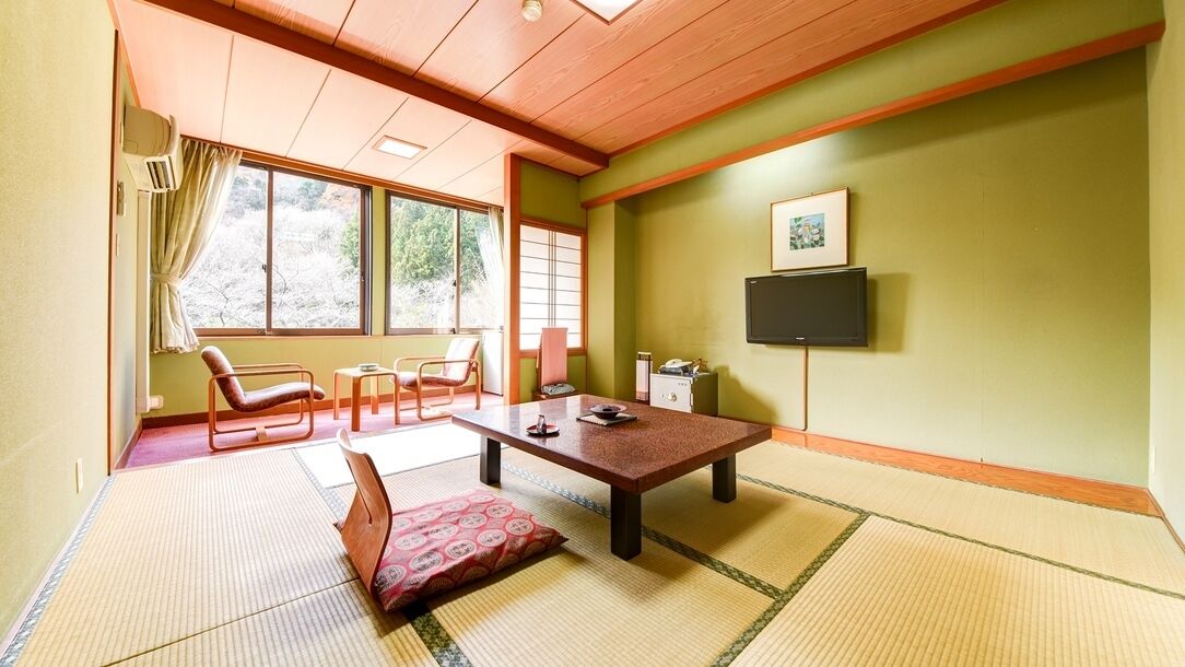A traditional Japanese room with tatami flooring, a low wooden table, and a television mounted on the wall.