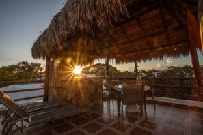 Relax on the tranquil outdoor space with a thatched roof, overlooking the surrounding landscape.