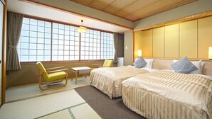 Una habitación de hotel de estilo tradicional japonés con suelo de tatami, futón, un escritorio de madera bajo y una puerta corrediza tipo shoji.