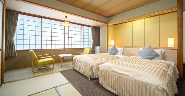 A traditional Japanese-style hotel room with tatami flooring, a futon bed, a low wooden desk, and a sliding shoji screen door. - Hotel Kameya (Osaki)