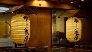 Dos faroles de papel iluminados con caracteres japoneses, vigas de madera y una decoración de interiores tradicional.