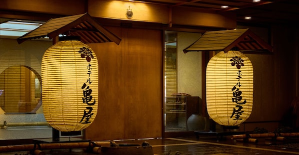 Two illuminated paper lanterns with Japanese characters, wooden beams, and a traditional interior design. - Hotel Kameya (Osaki)