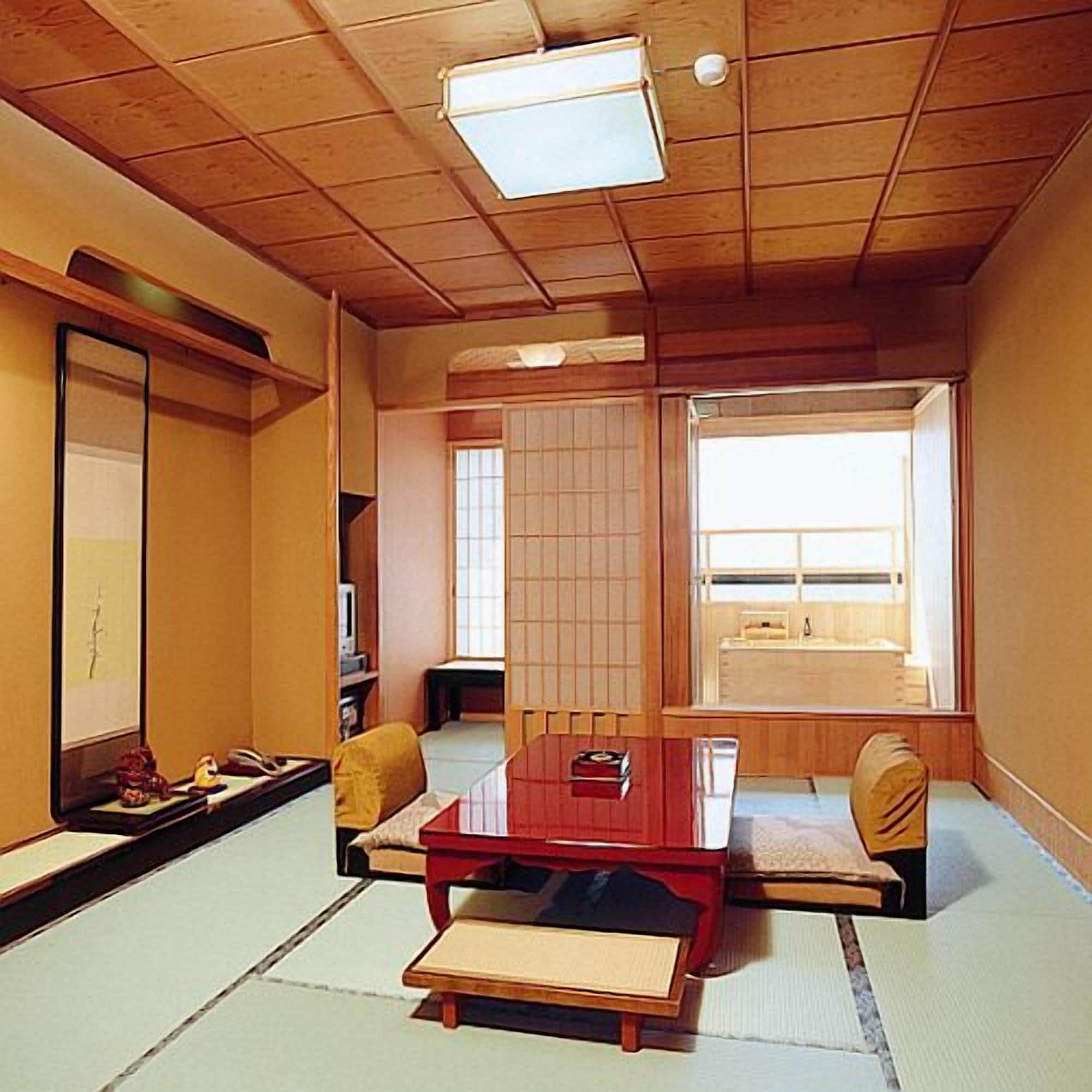 Habitació tradicional japonesa amb fons de tatami, una taula de fusta baixa, un sofà i una porta corredissa.