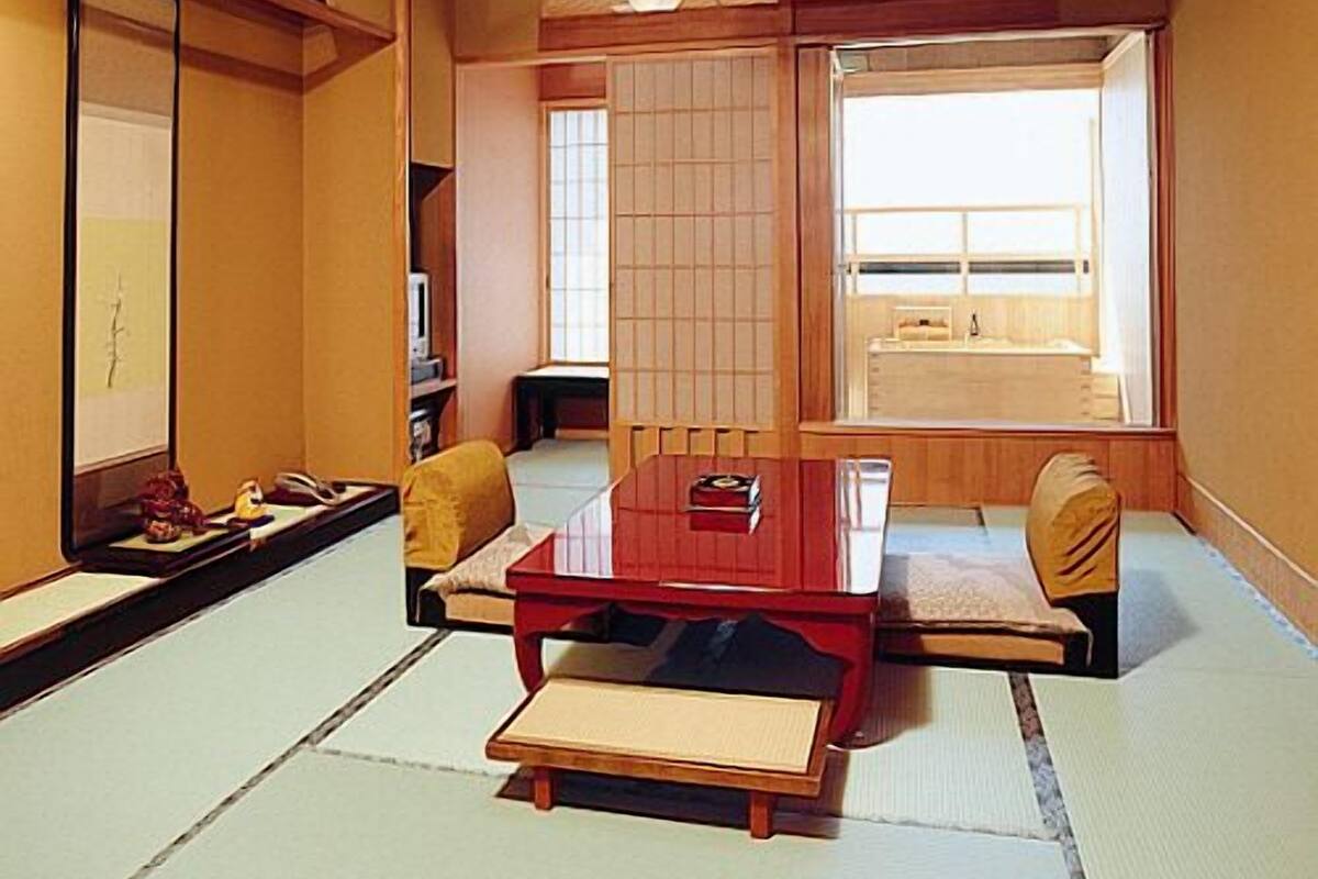 A traditional Japanese room with tatami flooring, a low wooden table, a sofa, and a sliding door.