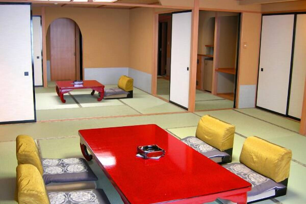 A traditional tatami room with a red table, low cushions, and sliding doors.