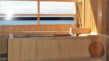Una sauna de madera con un banco, un lavabo y vistas al agua.