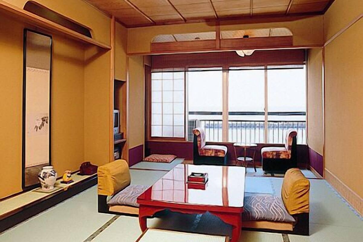 A traditional Japanese room with tatami flooring, low tables, and cushions.