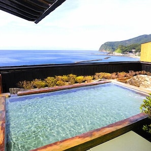 A clear swimming pool with a view of the ocean and hills.