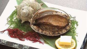 A plate with a shell, greens, and a lemon wedge.