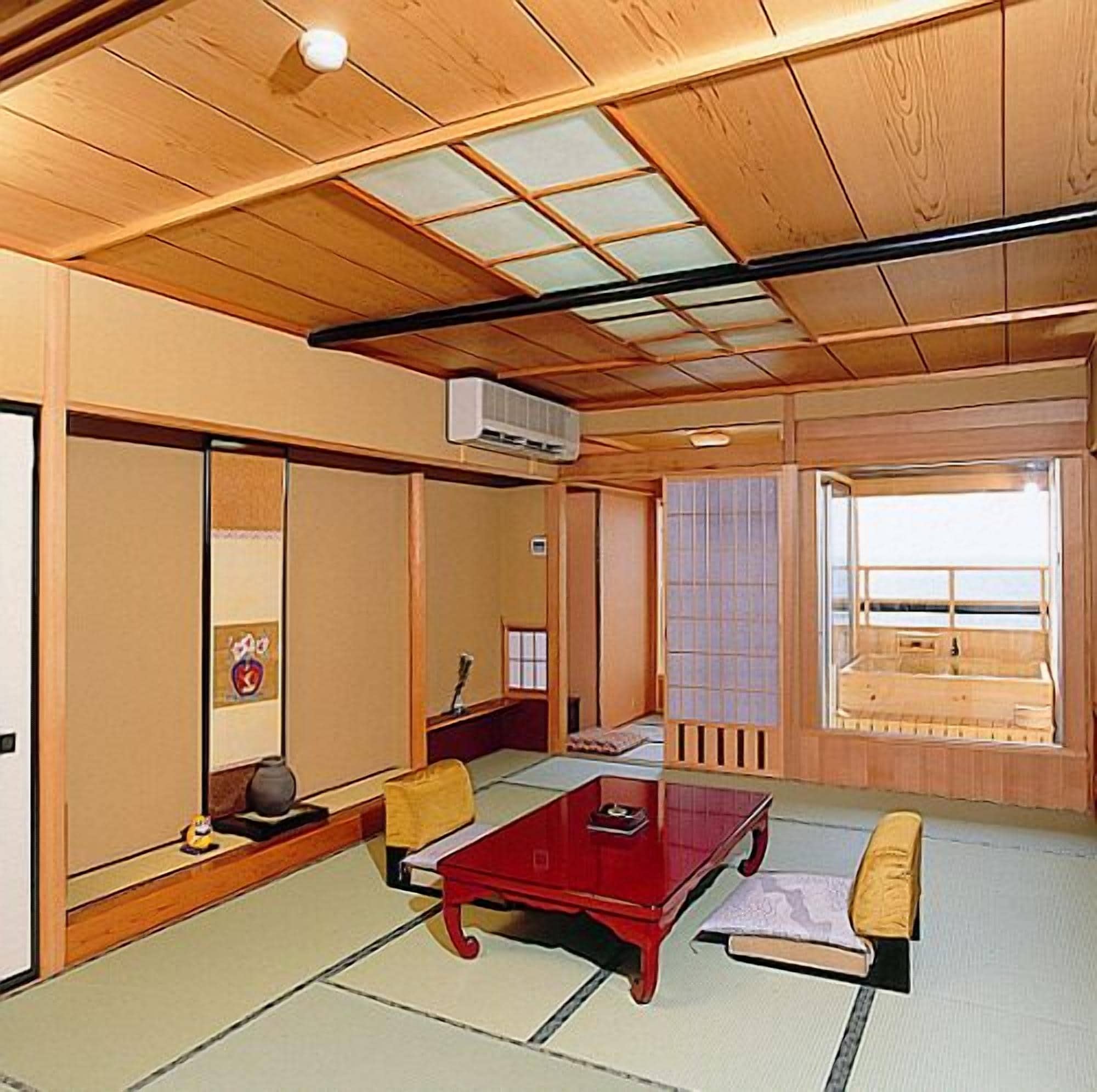 Una habitació japonesa tradicional amb tatami, una taula de fusta baixa i vista al mar a través d'una porta corredissa.