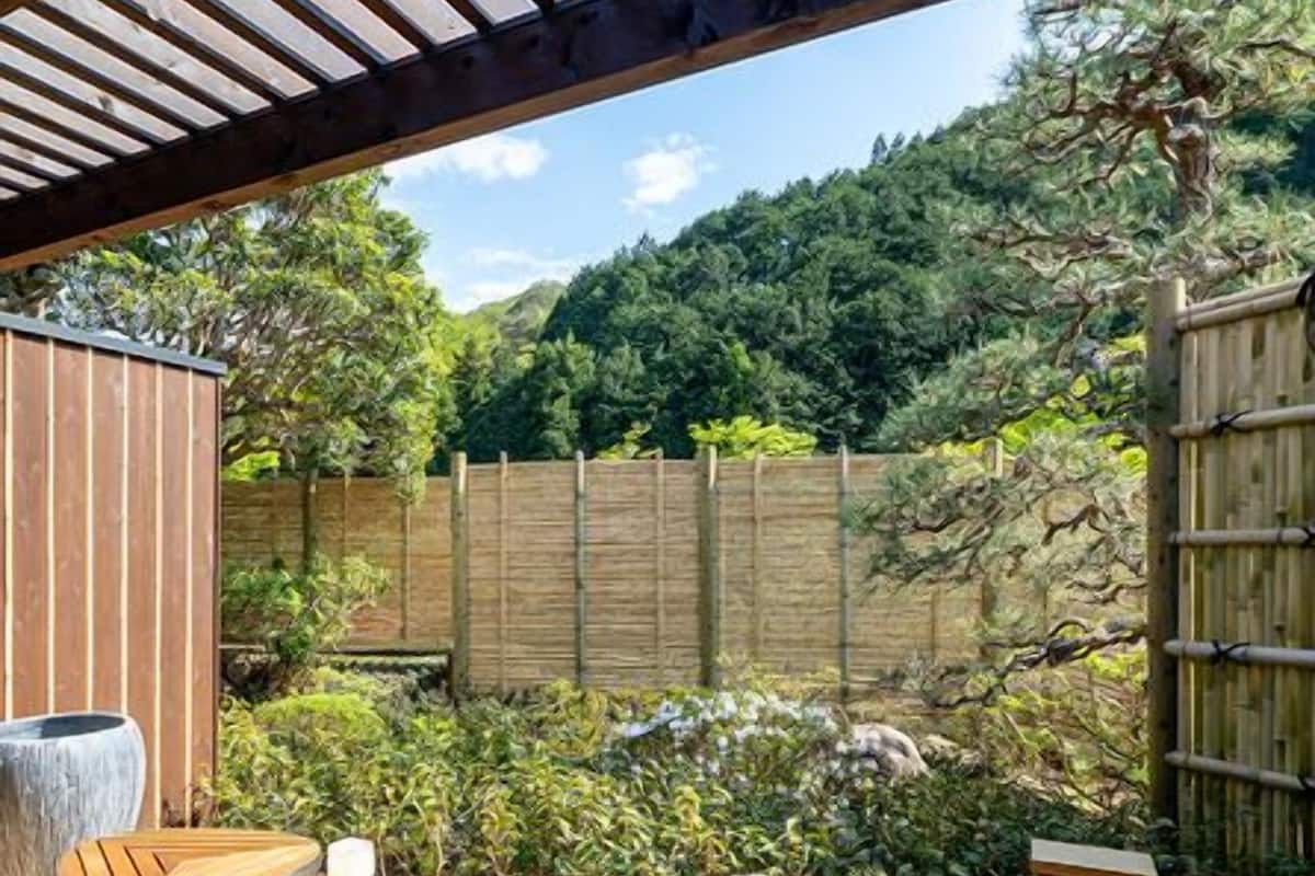 Eine Holzterrasse mit Whirlpool, Sitzgelegenheit und einem Steingarten.