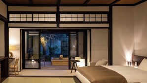 A traditional Japanese-style bedroom with tatami flooring, a sliding door leading to a balcony, and a bed with a wooden headboard. - Shirakabeso (Izu)