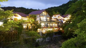 A multi-story hotel with a traditional architectural style, located beside a flowing river. - Shirakabeso (Izu)