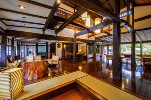 A spacious interior with high ceilings, wooden beams, and a central seating area with cushions. - Shirakabeso (Izu)