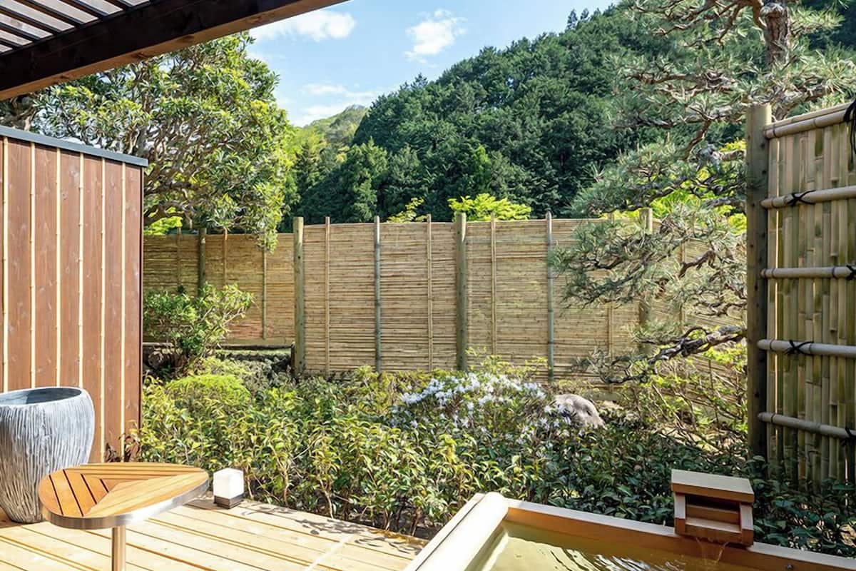 Eine Holzterrasse mit Whirlpool, Holztisch und einem großen Blumentopf.