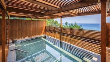 A wooden deck with a pool, wooden railings, and a view of the ocean.