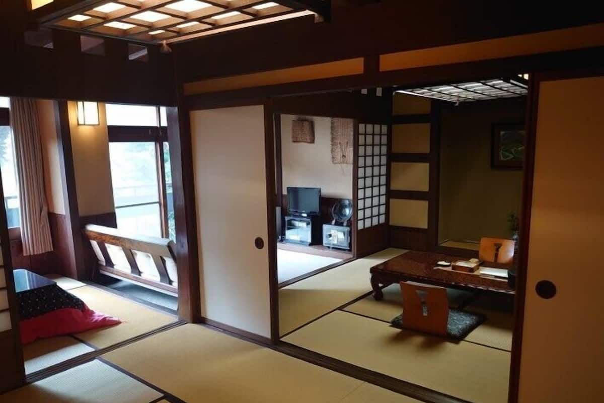 Ein traditioneller japanischer Raum mit Tatami-Boden, einem niedrigen Tisch und verschiebbaren Türen.