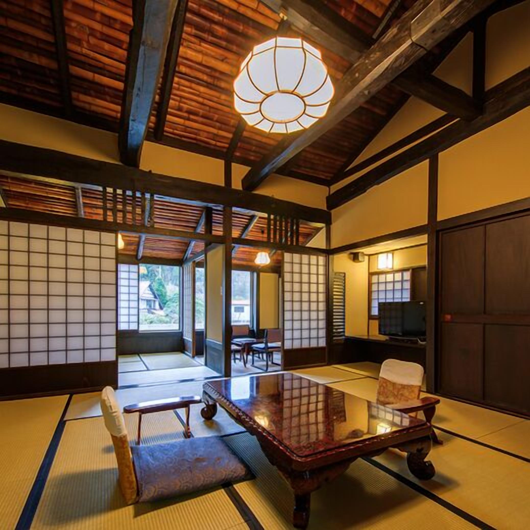 Een traditionele Japanse kamer met tatami vloerbedekking, een lage tafel, een stoel en een hanglamp.