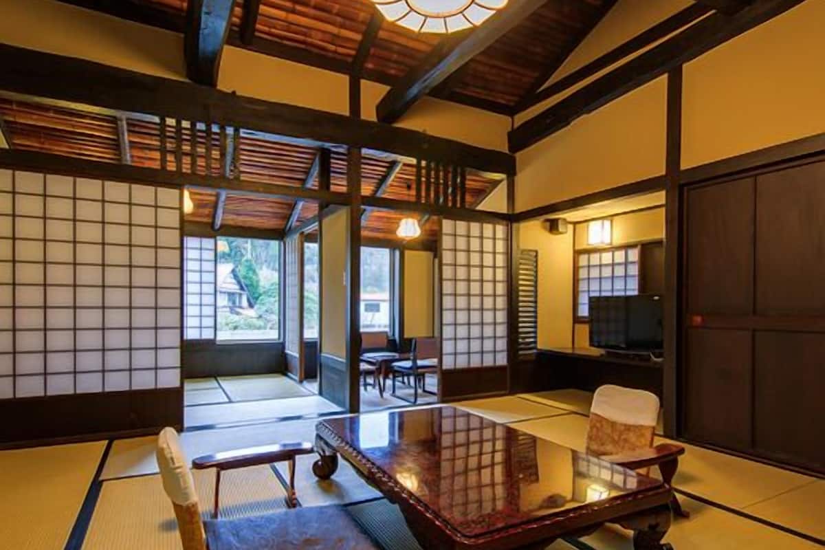 Ein traditioneller japanischer Raum mit Tatami-Boden, einem niedrigen Tisch, einem Stuhl und einer hängenden Leuchte.