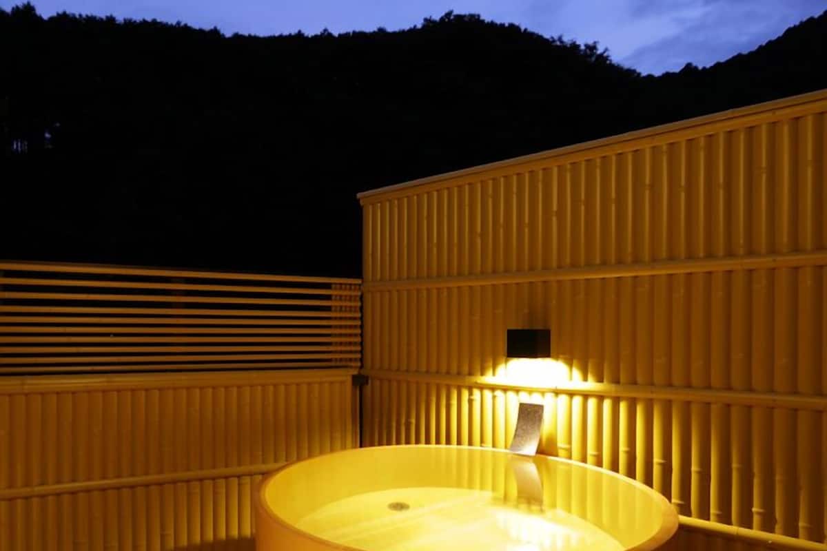 Ein holzgefasstes, fassförmiges Whirlpool mit einer Lampe obenauf, umgeben von Holzverkleidungen.